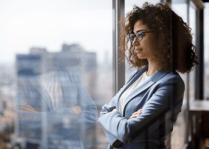 Professional woman looking out window with arms crossed